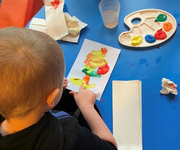 child doing finger painting at table